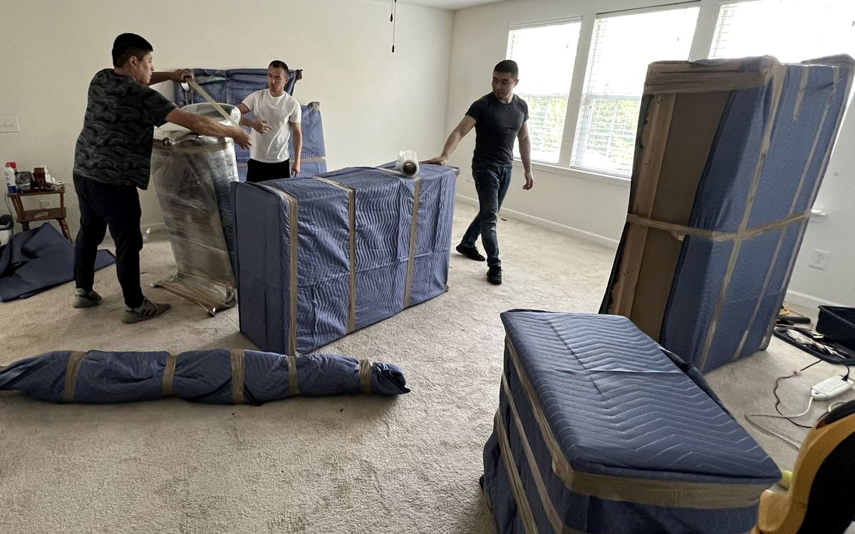 Sky 7 crew wrapping a bedroom set in blue moving blankets and tape